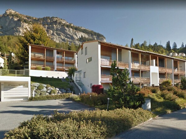 Un hôtel moderne avec une vue imprenable sur les montagnes, composé d’un bâtiment principal doté de balcons et d’une annexe plus petite.