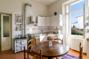 A kitchen with white cabinets, a stove, a sink, and a window with a view of buildings. - A charming, detached, 200-square-meter period house on three levels, accommodating up to 10 people.The property is located in Gravedona e Uniti, a charming village on the northwest shore of Lake Como, known for its historic center and picturesque lakefro (Gravedona ed Uniti)