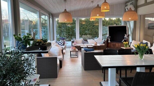 A spacious indoor area with large windows, wicker furniture, and hanging pendant lights. - 3-person holiday apartment with balcony (Debki)