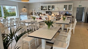 A modern dining area with white furniture, pendant lighting, and a view of the kitchen area. - 3-person holiday apartment with balcony (Debki)