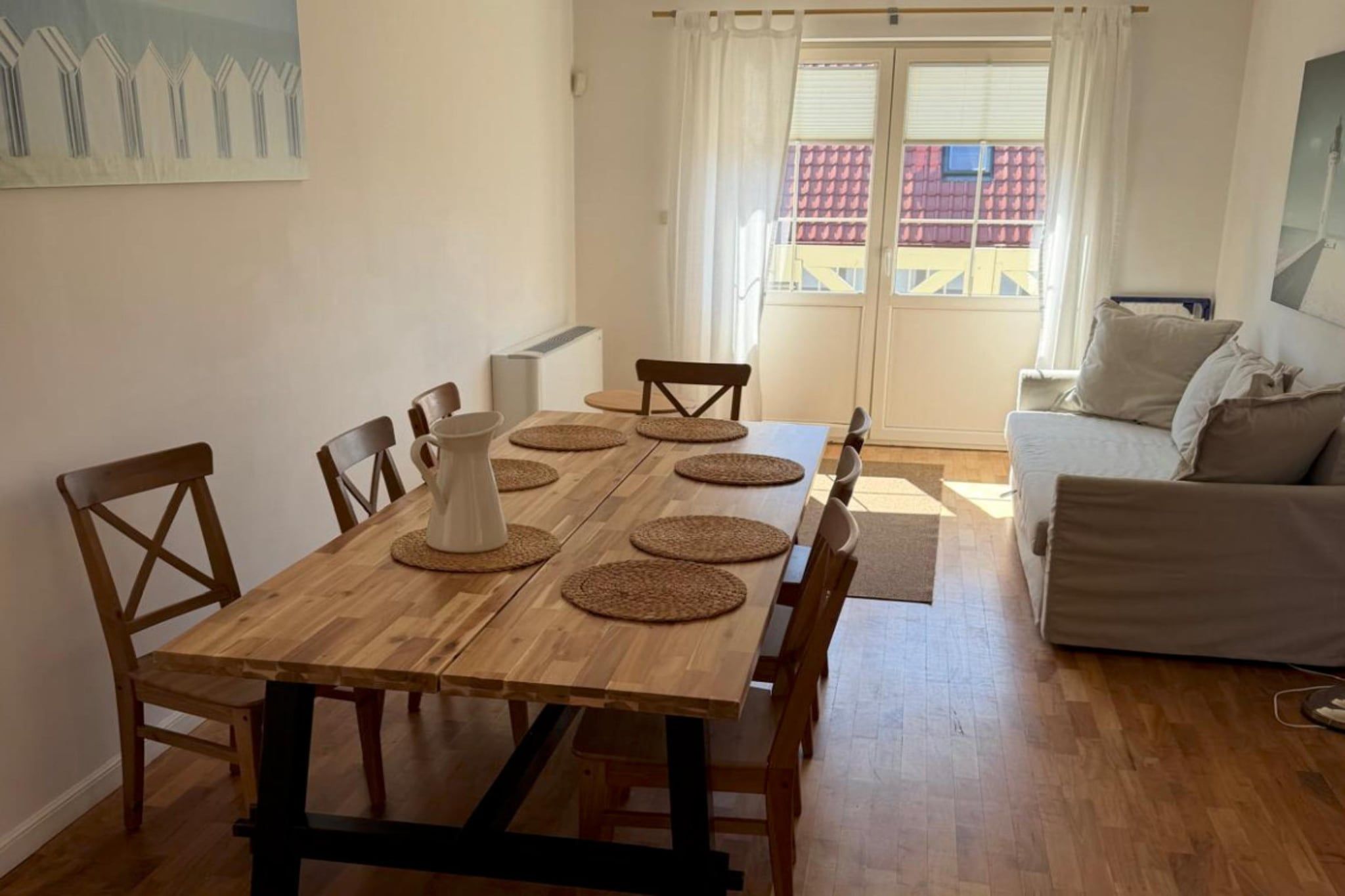 Un coin repas avec une table en bois, des chaises et un pichet blanc.