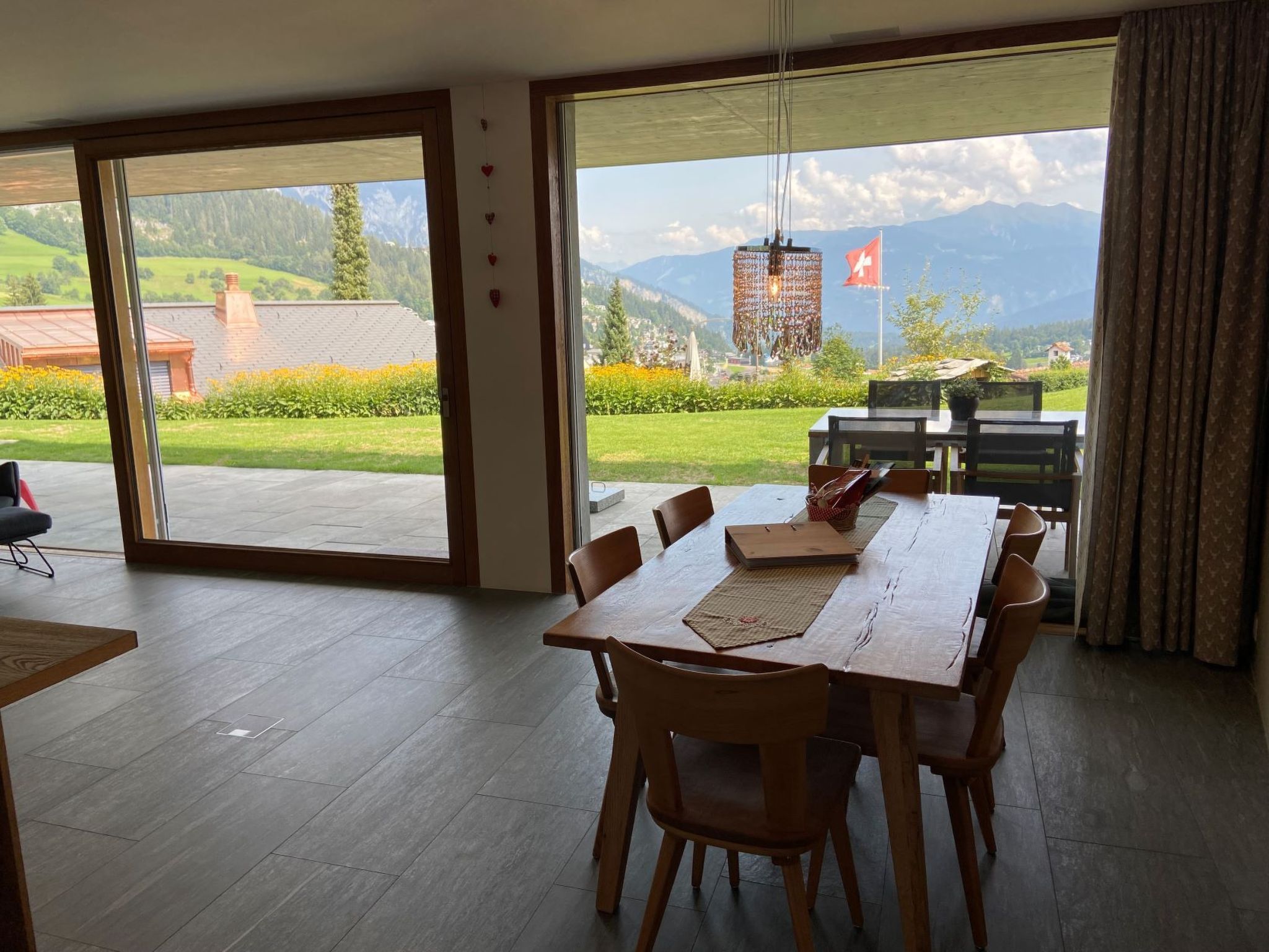 Un espace repas comprenant une table et des chaises, de grandes portes-fenêtres coulissantes donnant sur un jardin avec vue sur la montagne.