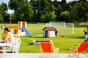 An outdoor playground with a slide, a small shed, and a soccer goal. - Large, comfortable apartment for 6 people (Debki)