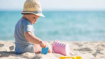 Ein Kind spielt mit Sandspielzeug am Strand.