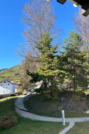 Ein Weg führt zu einem Gebäude mit einem eingezäunten Bereich, umgeben von Bäumen und einer hügeligen Landschaft.