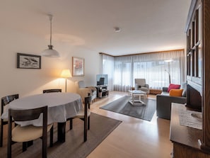Een moderne woonkamer met een eettafel, banken, een televisie en kunstwerken aan de muren.