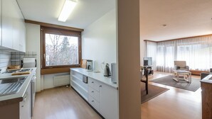 Una cocina moderna con estufa integrada, cafetera y ventana con vista a árboles.