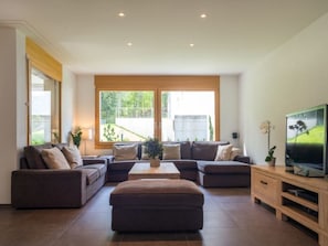 Ein modernes Wohnzimmer mit einem Ecksofa, einem Couchtisch und einem Fernseher auf einem Holzboden.