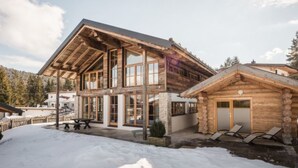 A log cabin with a large porch, a dining area, and a small adjacent building with a covered porch.