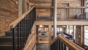 A multi-level wooden interior with a staircase, a balcony, and a seating area.