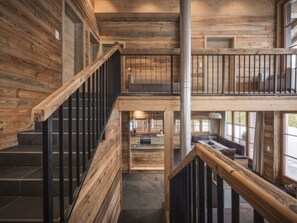 Un interior de madera con varios niveles, una escalera, un balcón y una zona de estar.