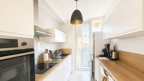A modern kitchen with white cabinetry, a black oven, a wooden countertop, and a pendant light. - Sea view apartment, quiet residence, 10 minutes from the center and beaches. (Bandol)