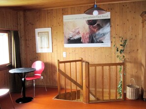 Ett rum med träväggar, en trappa, ett matbord med stolar och en affisch på väggen.