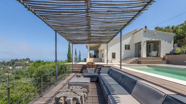 A covered outdoor seating area with a pool, a white building, and a view of the landscape. - Villa with Pool and Spectacular Sea Views (Sa Riera)