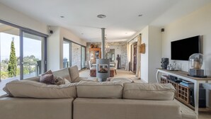A modern living room with a sectional sofa, a fireplace, a television, and large windows offering a city view. - Villa with Pool and Spectacular Sea Views (Sa Riera)
