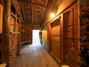 A rustic wooden interior with a bench, wooden walls, and a broom. - Maiensäss Plausi, (Buchen), plausi_buchen by Interhome (Buchen im Prättigau)