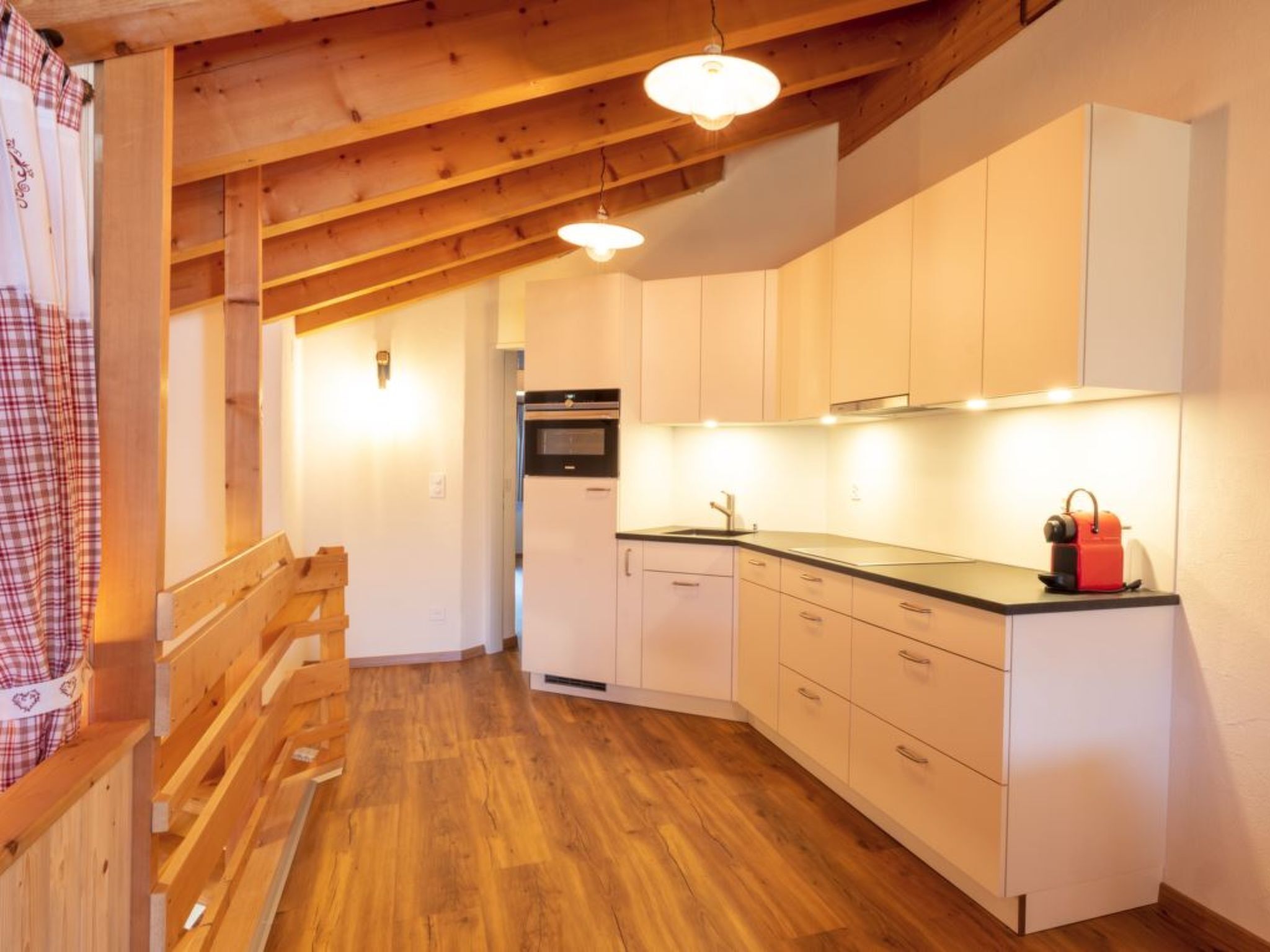 A kitchen with wooden beams, white cabinets, and a wooden bench.