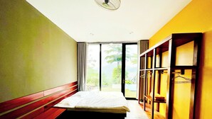 Ein Hotelzimmer mit Bett, Fenster, Ventilator und Kleiderschrank.