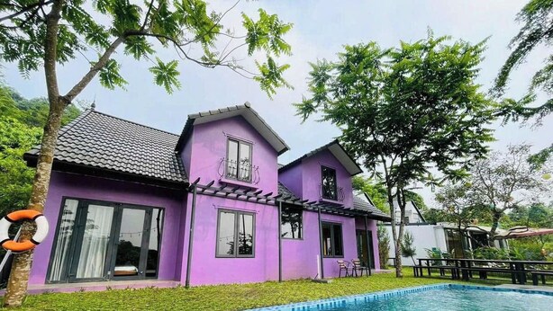 Ein zweistöckiges Haus mit Swimmingpool, umgeben von Grünflächen und Bäumen.