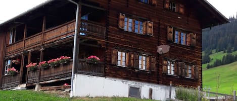 A wooden chalet with a balcony, multiple windows, and a satellite dish.