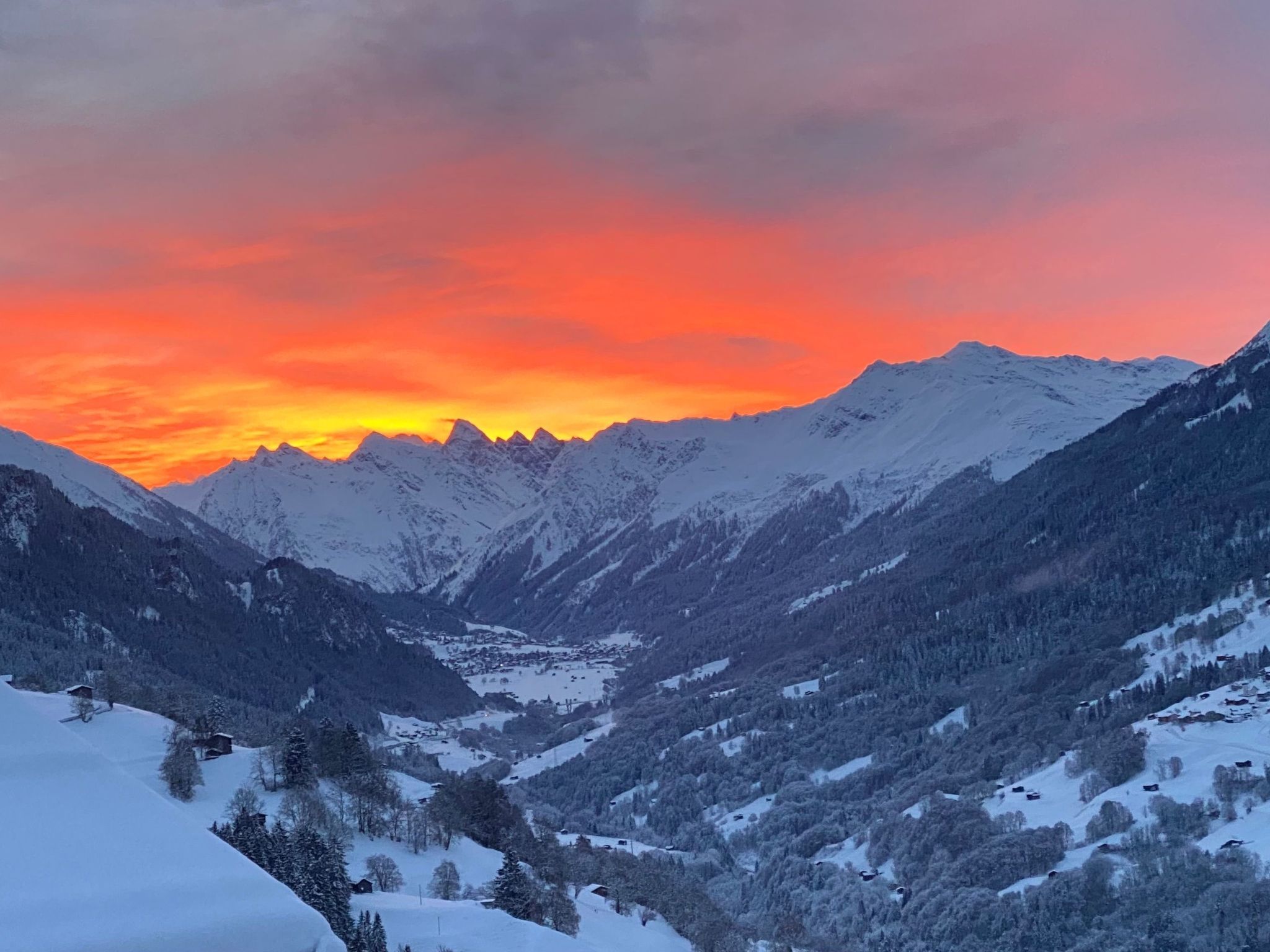 A mountainous landscape with snow-covered peaks and a valley.