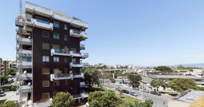 A multi-story building with balconies, a visible construction crane, and a clear view of the surrounding urban area. - Michi’s Attic by Propertize (Cagliari)