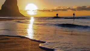 A beach with a large rock formation and the sun setting over the ocean. - Villa Cruz - PlusHolidays by Interhome (Calpe/Calp)