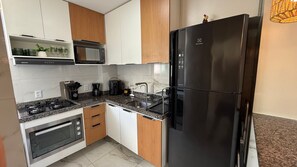 Una cocina moderna con un refrigerador negro, un microondas, una estufa y una cafetera.