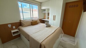 Quarto com cama, janela, guarda-roupa e estante.