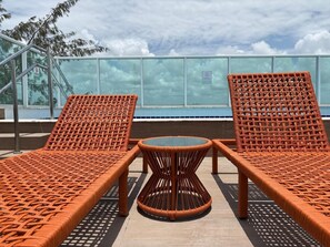 Una terraza en la azotea con dos sillones de mimbre y una mesita redonda.
