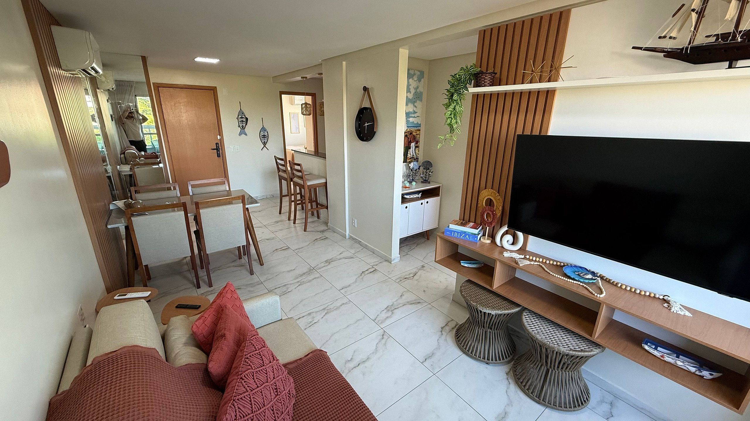 A living room with a TV, seating area, and a dining space.