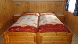 Un lit double en bois, recouvert d’une couvre-lit à motifs, deux tables de chevet et un mur en bois.