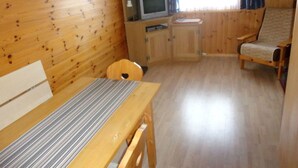 L’intérieur d’un chalet en bois, avec un lit, un téléviseur, une chaise et une table.
