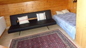 Une pièce en bois avec un lit, un canapé et un tapis à motifs.