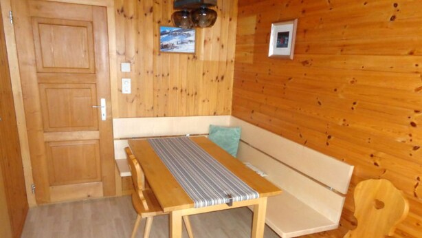 Un intérieur en bois avec une table, un banc et des chaises.