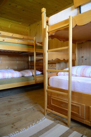 Une cabane en bois avec des lits superposés, un plancher en bois et un aménagement intérieur simple et rustique.
