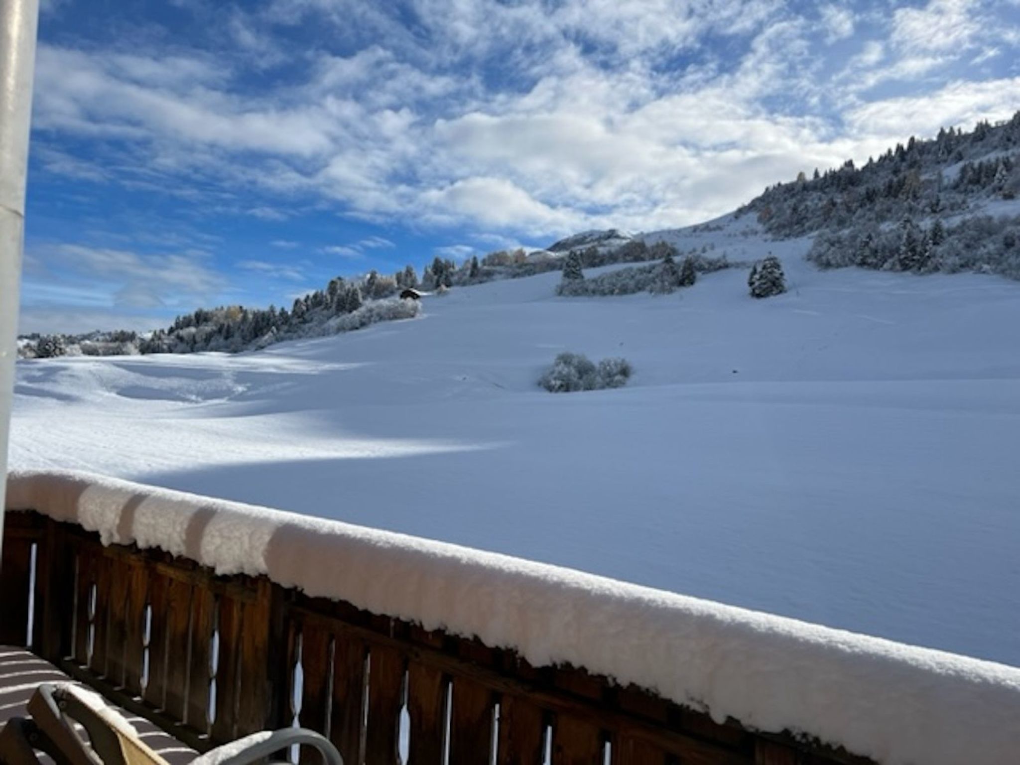 A snowy landscape with a wooden fence in the foreground and a clear sky.