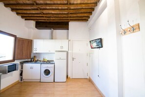 Eine kleine Küche mit Waschmaschine, Mikrowelle und kleinem Kühlschrank.
