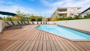 A rooftop pool with wooden decking, lounge chairs, and umbrellas. - Bright flat for 4 people, right next to the shops (Grasse)