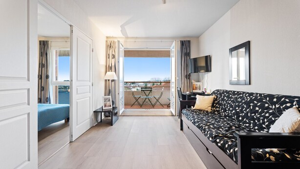 A hotel room with a balcony, a sofa, a table, and a TV. - Bright flat for 4 people, right next to the shops (Grasse)