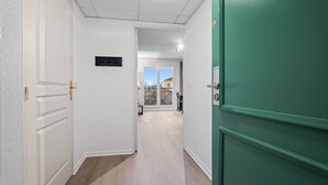 A hallway with a green door, white walls, and a view of a balcony with outdoor furniture. - Bright flat for 4 people, right next to the shops (Grasse)