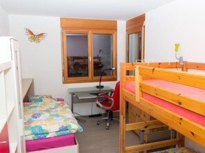 Una camera del dormitorio con letti a castello, una scrivania, una sedia e una finestra.