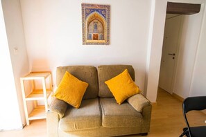 Ein Wohnzimmer mit einer Couch, zwei gelben Kissen, einem Holztisch und einer Wanddekoration.