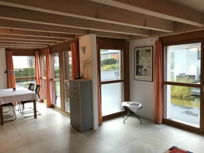 A room with a dining table, chairs, a cabinet, a small table with a chair, and large windows with curtains. - Ferienhaus Carrera mit Traumgarten, Valendas, (Valendas), 22007B by Interhome (Valendas)