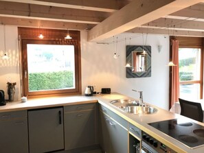Una cocina moderna con un amplio ventanal, pileta de acero inoxidable y electrodomésticos integrados.