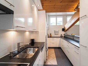 Eine moderne Küche mit weißen Schränken, einer schwarzen Arbeitsplatte und einer Holzbalkendecke.