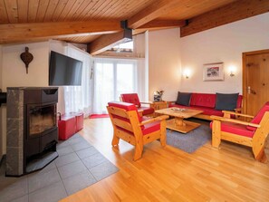 Ein gemütliches Wohnzimmer mit Kamin, Holzmöbeln und einem Fernseher.