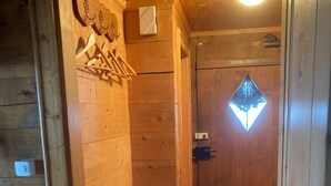 Puinen ovi, jossa on timantinmuotoinen ikkuna, ovikello ja seinään kiinnitetty valaisin.