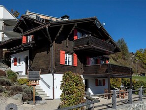 Una xalet tradicional amb teulada inclinada, balcons de fusta i una escala de pedra que condueix a l'entrada.
