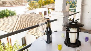 Un balcón con vistas a un paisaje urbano, una botella de vino, una copa y un candelabro con velas.